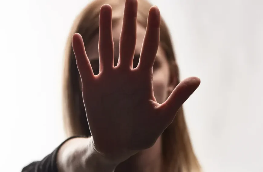 An image of a woman's face obscured by a hand