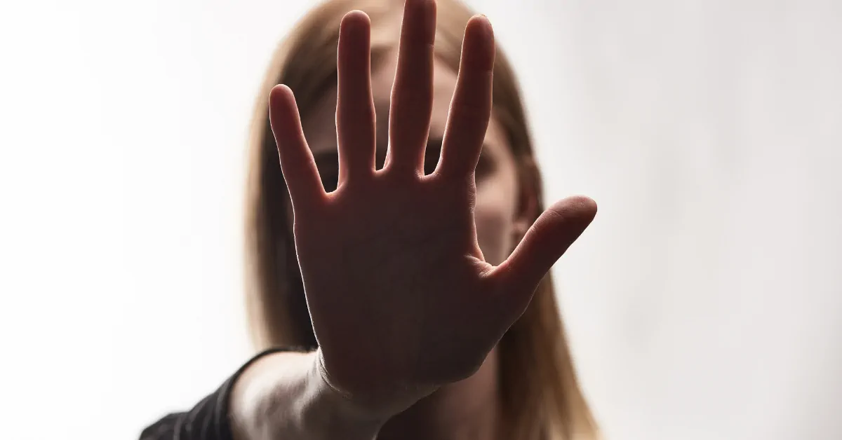 An image of a woman's face obscured by a hand