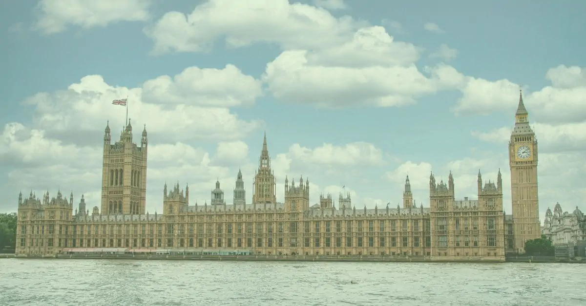 An armchair sat in the middle of the countryside with a lake behind.